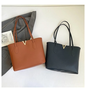 Detail of classic large tote bags in brown and black leather with gold V-shaped hardware