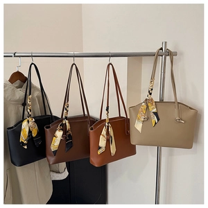 Row of leather tote bags in four colors with silk scarves hanging on a rack