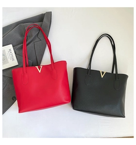 Detail of red and black leather tote bags featuring elegant gold V metal accents