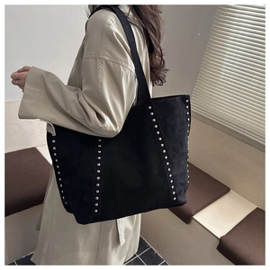 Detailaufnahme einer schwarzen Wildleder-Tote-Bag mit silbernen Nieten und Schultergurt
