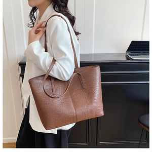 Brown crocodile pattern tote bag shown as a shoulder bag on a model in a minimalist setting