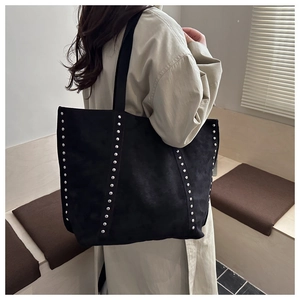 Detailansicht der silbernen Nieten an der schwarzen Wildledertasche zum beigen Trenchcoat