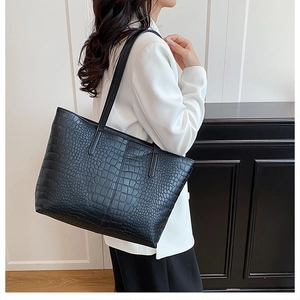 Close-up of black crocodile pattern faux leather texture on a large tote bag