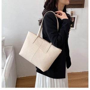 Detail of minimalist cream-white tote bag with crocodile texture worn by model