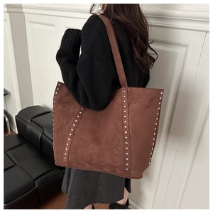 Detail der braunen Wildleder-Tote-Bag mit silbernen Metallnieten und Industrie-Stil