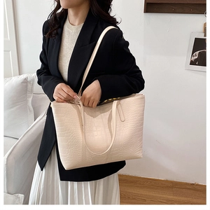 Detail of cream white faux crocodile leather tote bag with elegant embossed texture