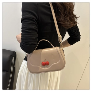 Detail of beige cherry accordion card bag showing the crossbody strap and top handle
