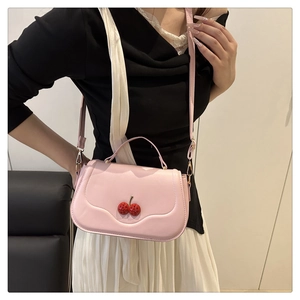 Close-up of pink shoulder bag with 3D cherry ornament and adjustable strap detail