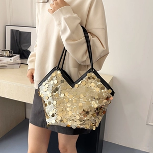 Large gold sequin tote bag with black leather straps shown on a female model