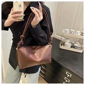 Détail du sac à bandoulière en cuir mat marron avec coutures fines et sangle nouée