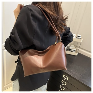 Detailed view of caramel brown hobo bag with knotted shoulder strap on model's shoulder