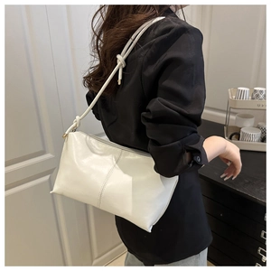 Detailed side view of a white soft leather shoulder bag with a stylish knotted strap
