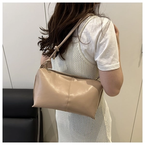 Close-up of beige minimalist shoulder bag with vertical stitching and knot strap detail