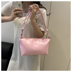 Detailed view of pink minimalist shoulder bag featuring knot handle and leather texture