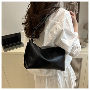 Detail of minimalist black shoulder bag featuring stylish knot decoration on the strap