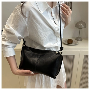 Gros plan d'un sac bandoulière noir minimaliste avec couture verticale sur cuir