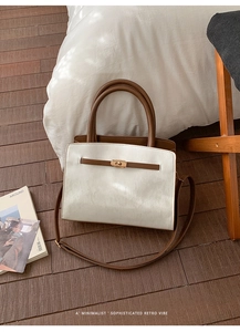 Détail d'un sac à main bicolore avec fermoir rotatif doré sur un fond en bois rustique