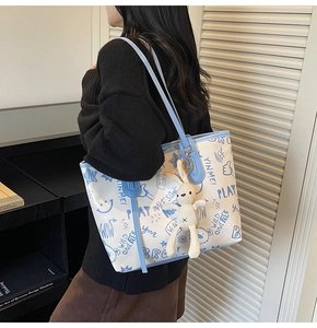 Détail du sac cabas blanc avec imprimés graffiti bleus et pendentif lapin en peluche