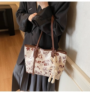 Détail du sac cabas blanc avec imprimé graffiti, poignées en cuir marron et breloque lapin