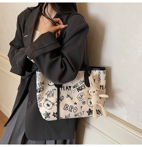Détail du sac cabas crème avec imprimé graffiti noir et breloque lapin en peluche sur l'anse