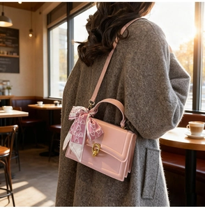 Detail of light pink square crossbody bag with silk scarf handle and golden U-clasp