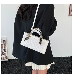 Detailed view of white luxury handbag with grid embossing and colorful silk scarf detail