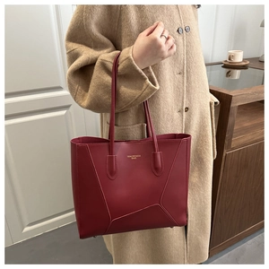 Elegantly designed burgundy leather tote bag featuring gold lettering and geometric stitching