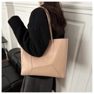 Detail view of large beige tote bag with geometric stitching and smooth leather texture