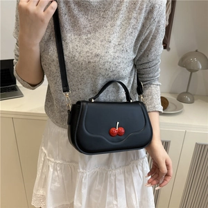 Elegant black cherry-themed handbag with red hardware and adjustable shoulder strap