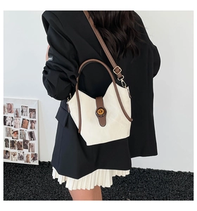 Detail of a beige and brown color-block shoulder bag shown on a model from the back