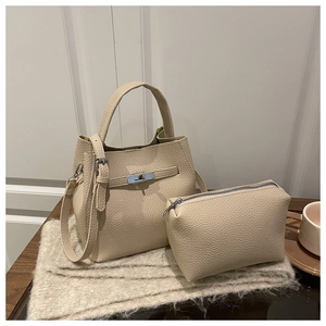 Detail of cream-colored pebble leather bucket bag with inner pouch and metal turn lock
