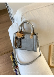 Détail du sac à main argenté métallisé à rayures verticales et pendentif en peluche