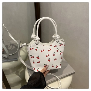 Detail of white cherry print bucket bag showing PU leather texture and stylish knot handle