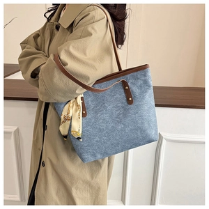 Blue canvas tote bag with brown leather strap and decorative patterned silk scarf detail