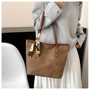 Detail of a brown tote bag featuring a decorative vintage chain pattern silk scarf