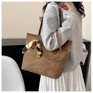 Brown suede tote bag detail with vintage chain pattern silk scarf tied on the handle