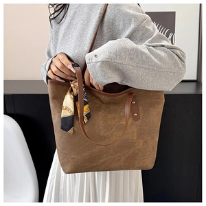 Close-up of brown large tote bag with silk scarf decoration and metal rivets detail