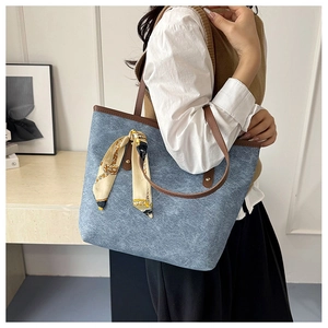 Detail of blue denim tote bag with leather strap and decorative printed silk scarf