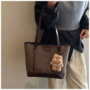 Détail du cabas en daim avec logo embossé et charmant ours en peluche marron