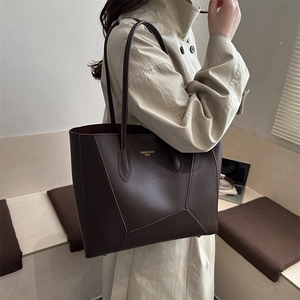 Deep brown matte leather tote bag with geometric stitching shown on a model