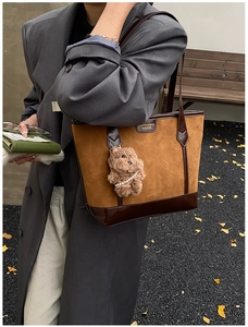 Détail du sac cabas en daim marron avec garniture en cuir contrasté et charm d'ours mignon