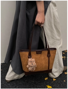 Détail du sac cabas marron en daim avec motifs de chats embossés et breloque ours