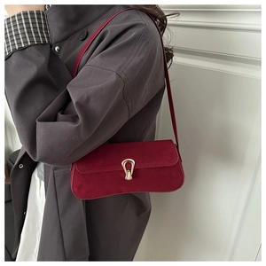 Detail showing high-quality burgundy suede baguette bag with golden horseshoe clasp