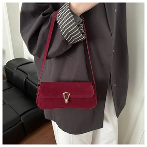 Model wearing a vintage burgundy suede baguette bag with a stylish gold clasp