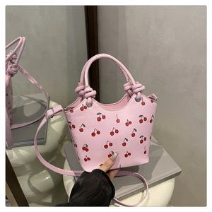 Detail of pink cherry print tote bag featuring a knotted handle and metal ring accents