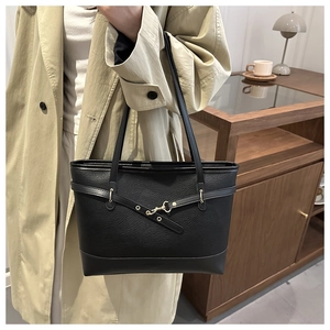 Close-up of black lychee grain leather tote bag with elegant gold buckle and shoulder strap