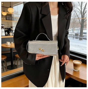 Detail of silver woven leather handbag featuring a stylish gold knot twist lock closure