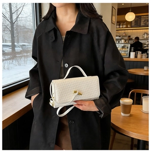 Detail of white woven leather texture with gold metal buckle on a square handbag