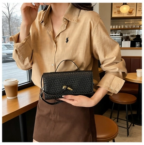 Macro detail of black woven leather texture and elegant gold knot twist lock closure