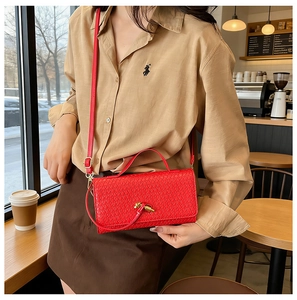 Macro view of red woven texture handbag with metal turn-lock and handle detail